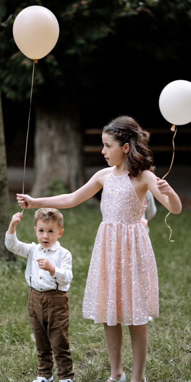 Zwei Kinder halten Luftballons bei einer Hochzeitsfeier, während sie den besonderen Moment genießen.